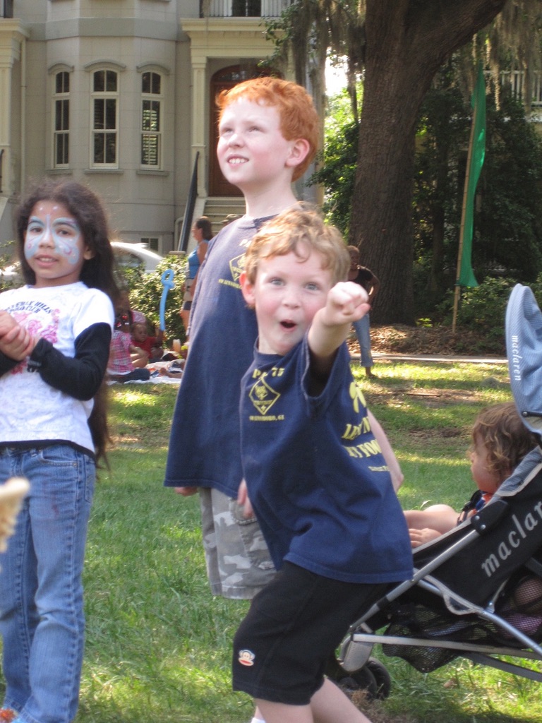 A childhood photo of Sam excitedly pointing toward the camera at an outdoor gathering