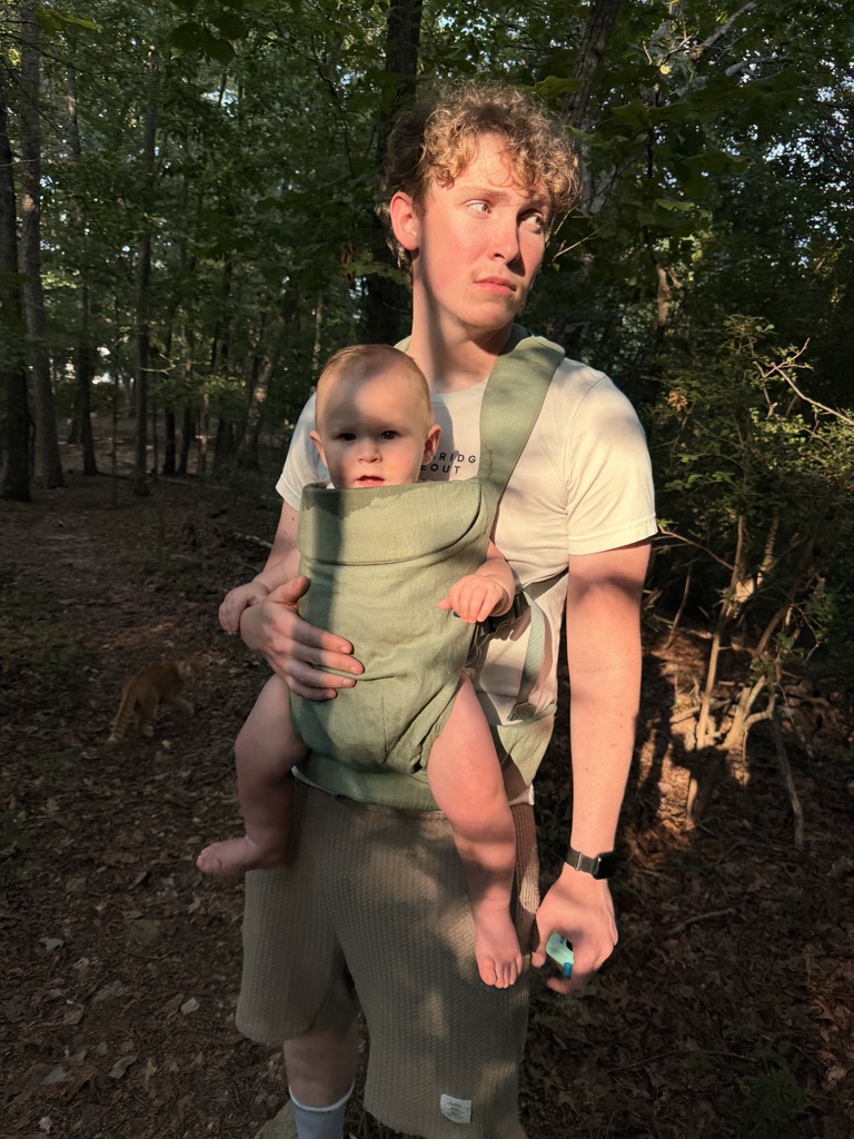 Sam carrying his baby during a walk in the woods